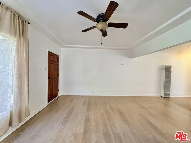 an empty room with wooden floor and a ceiling fan