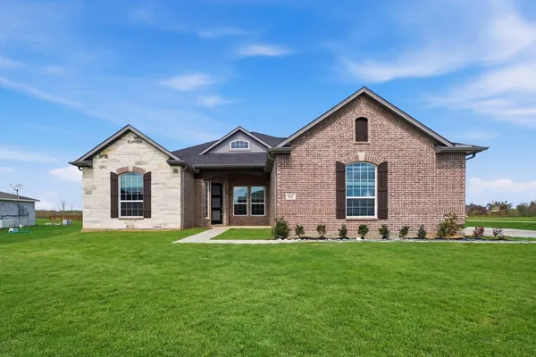 a front view of a house with a yard and trees