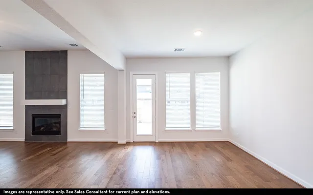 an empty room with windows and fireplace