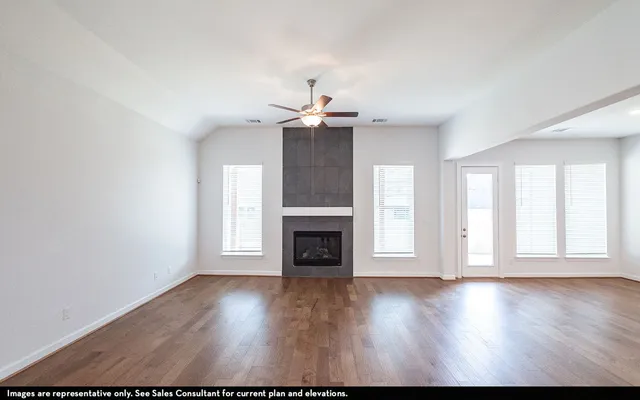 an empty room with windows fireplace and wooden floor