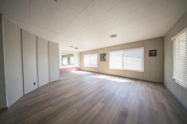 an empty room with wooden floor and windows