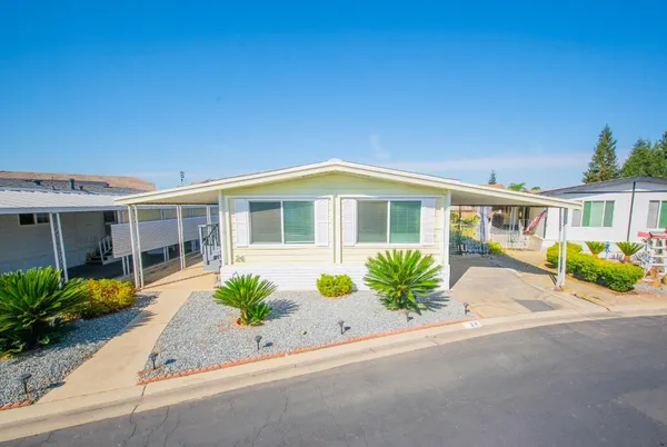 a front view of a house with a yard and potted plants