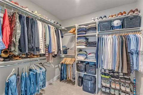 a view of walk in closet with clothes and shoes