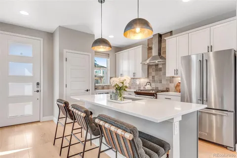 a kitchen with stainless steel appliances a dining table chairs and wooden floor