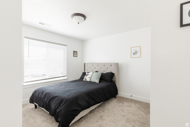 349 West 3085 South Logan, UT 84321 - Photo 24 of 37 Bright bedroom featuring a large window with horizontal blinds, neutral carpeting, white walls, and a ceiling-mounted light fixture