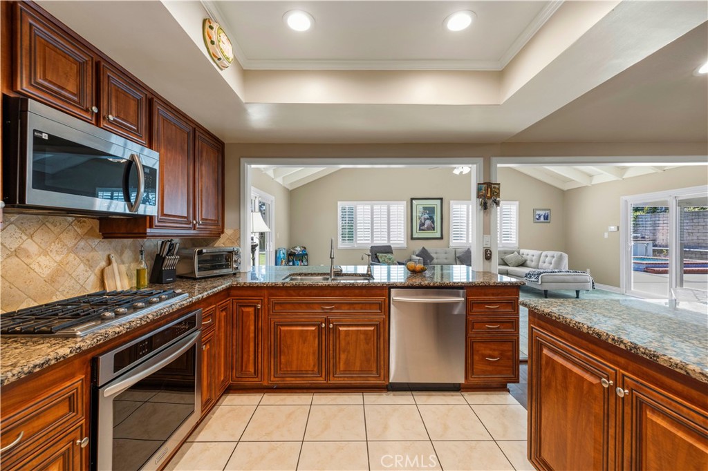 18770 Tribune Street Porter Ranch, CA 91326 - Photo 9 of 30 a kitchen with stainless steel appliances granite countertop a stove top oven a sink dishwasher and cabinets