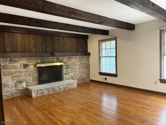 a view of an empty room with wooden floor and a fireplace