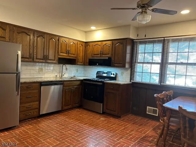 a kitchen with stainless steel appliances granite countertop a refrigerator a sink dishwasher a stove and a refrigerator