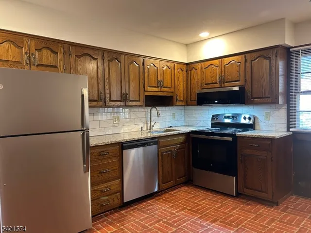 a kitchen with granite countertop wooden cabinets and a refrigerator