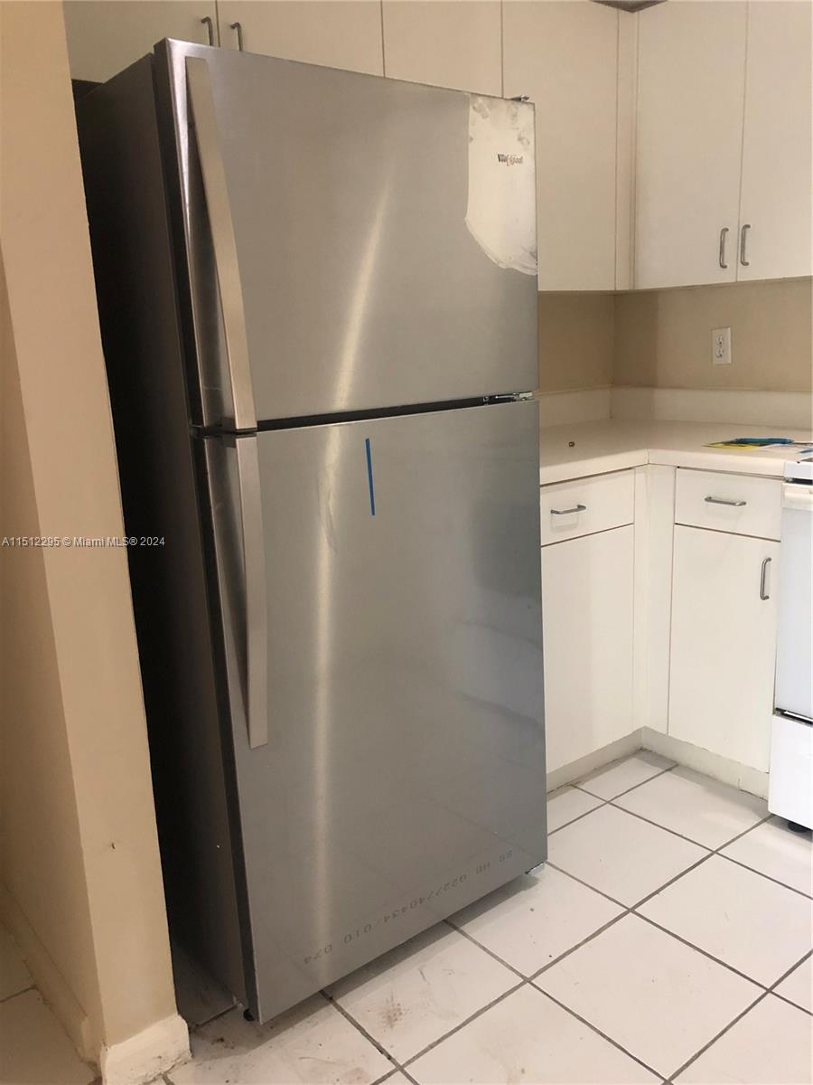 a view of a refrigerator in kitchen and white cabinets