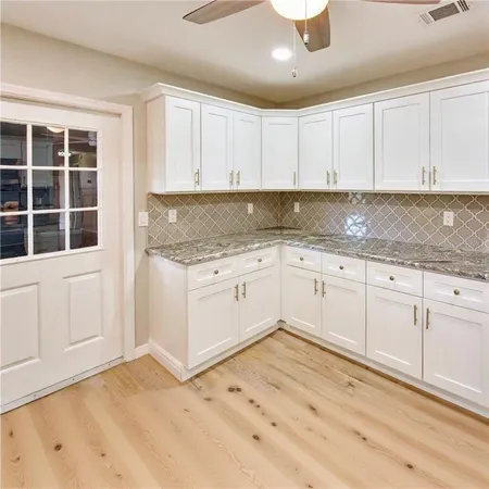 a kitchen with stainless steel appliances granite countertop a sink a stove a refrigerator a microwave oven with white cabinets