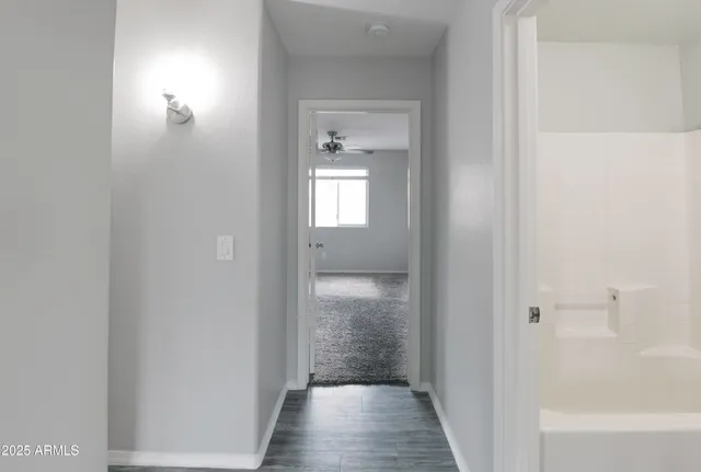 a view of a hallway with wooden floor and a bathroom