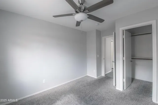 an empty room with a ceiling fan and carpet