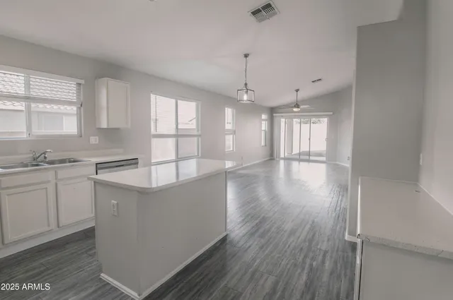 a large kitchen with cabinets wooden floor and a window