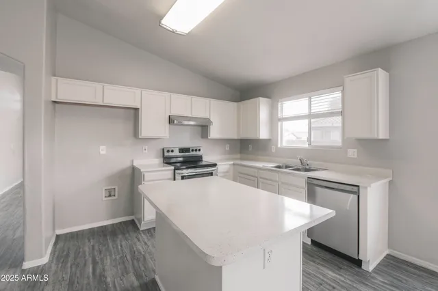 a kitchen with a sink a stove a refrigerator a center island and a window