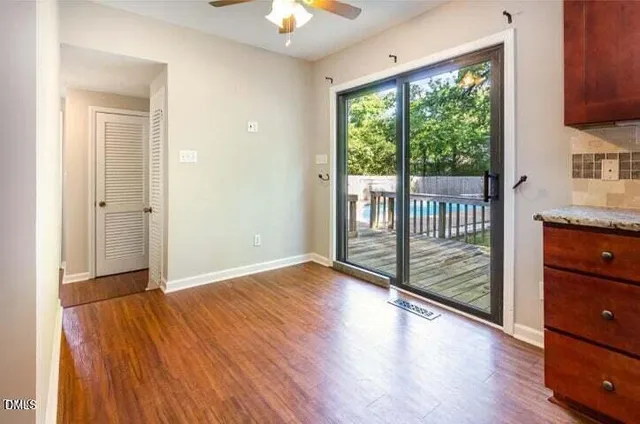 an empty room with wooden floor fan and windows