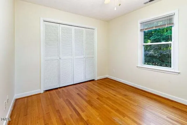 a view of an empty room with wooden floor and a window