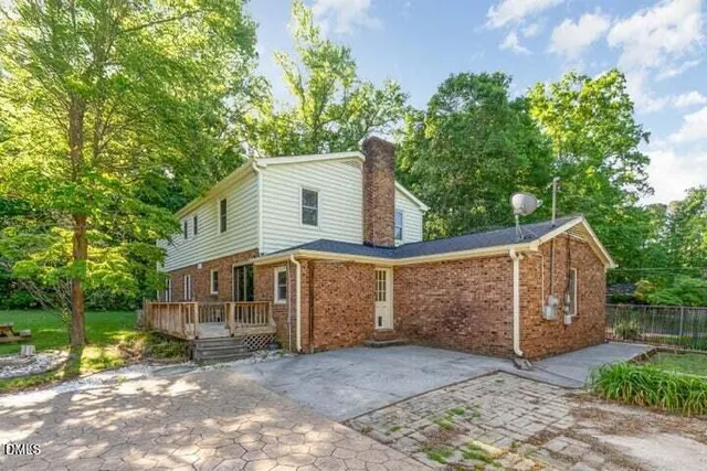 a view of a house with a yard plants and large tree