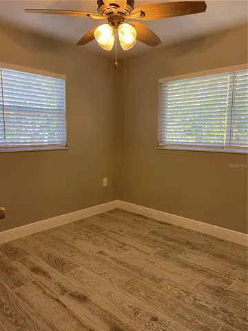 a view of an empty room with a window and wooden floor