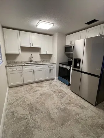 a large kitchen with granite countertop a stove a sink dishwasher and a refrigerator