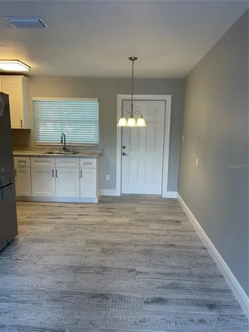 a view of a kitchen with granite countertop stainless steel appliances cabinets a sink and a wooden floor