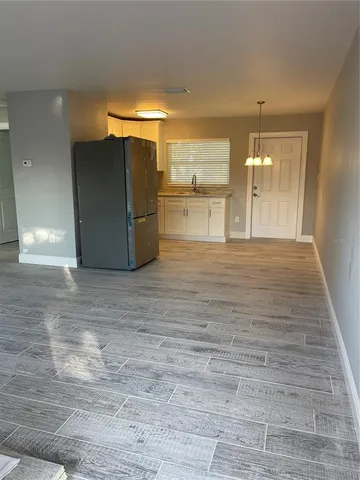 a view of a refrigerator in kitchen and an empty room
