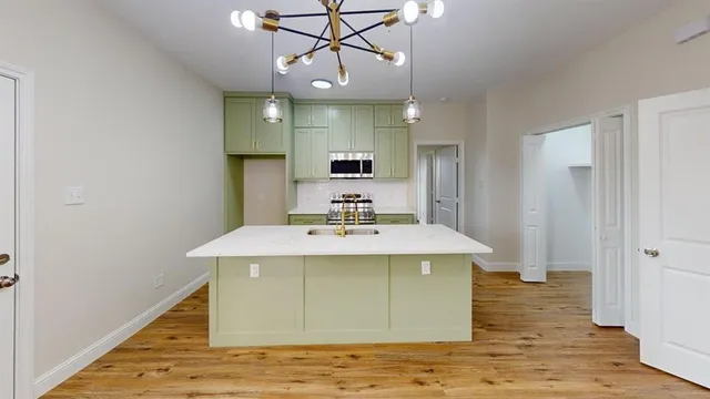 a kitchen with kitchen island stainless steel appliances a sink and wooden floor