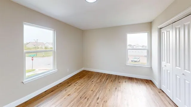 a view of an empty room with wooden floor and a window