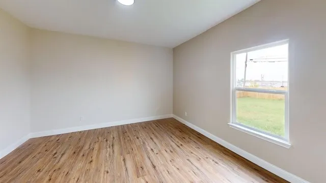 an empty room with a window and wooden floor