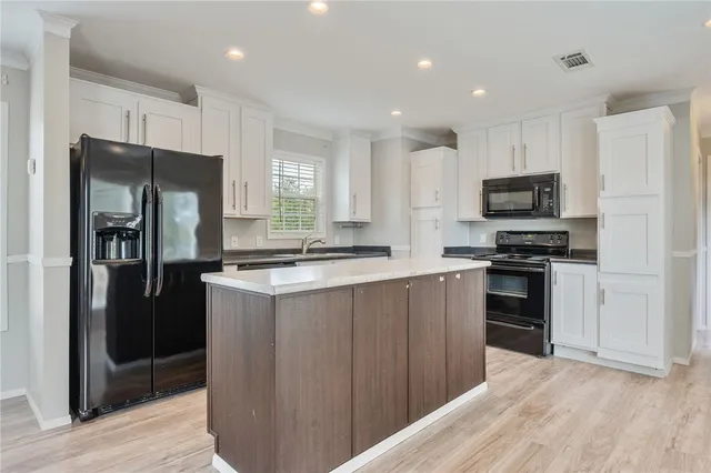 a kitchen with a refrigerator a stove top oven and wooden floor