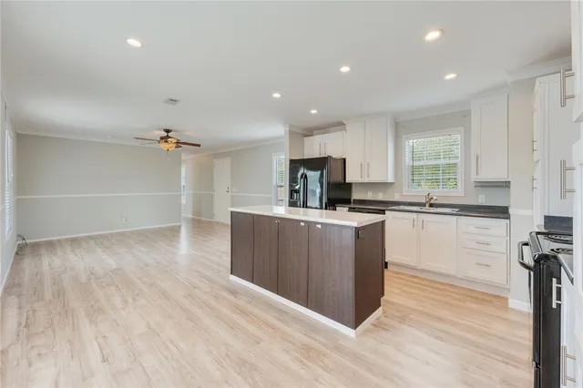 a kitchen with stainless steel appliances granite countertop a refrigerator a sink dishwasher a stove and white countertops with wooden floor