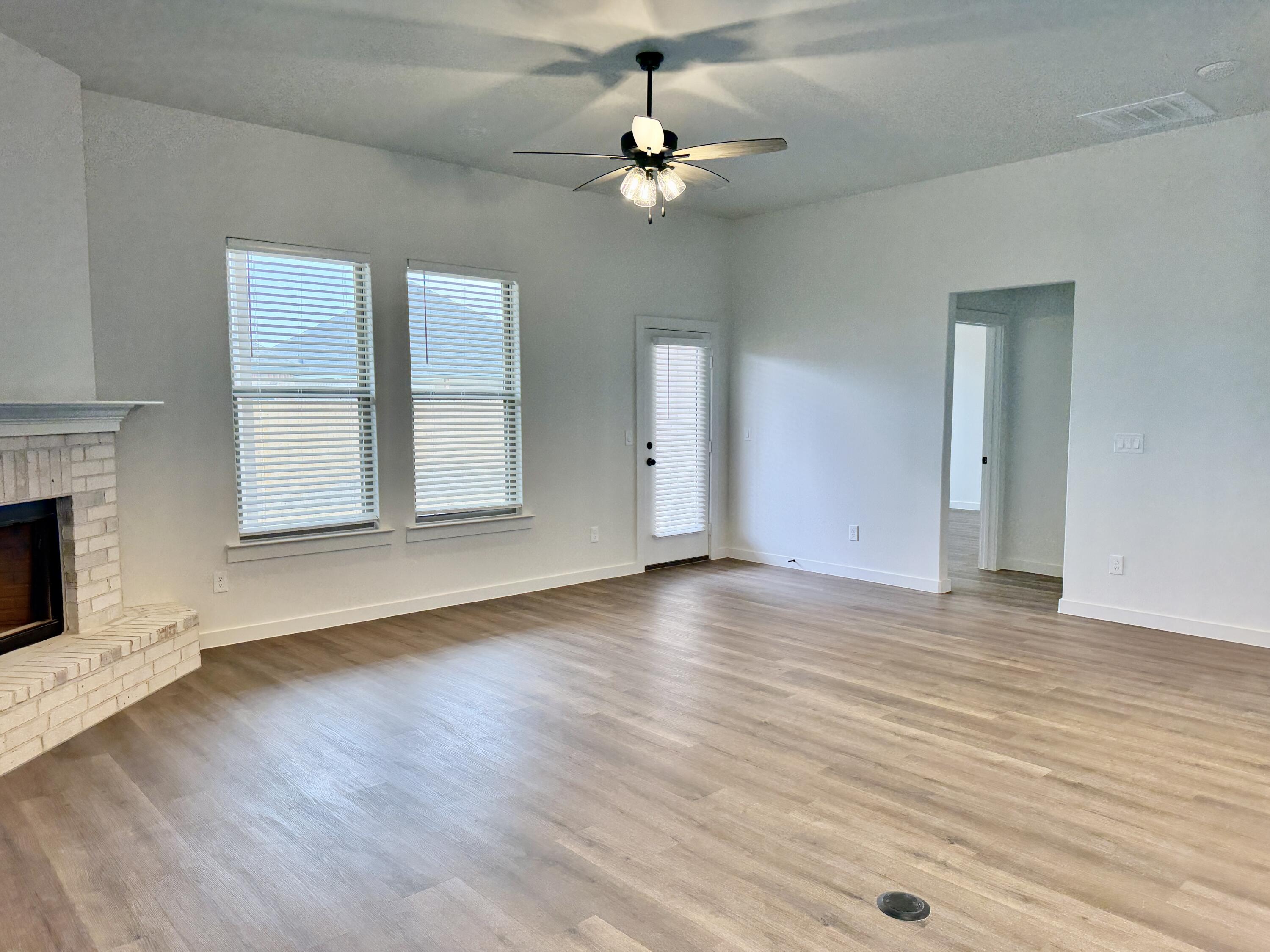 7007 16th Street Lubbock, TX 79416 - Photo 12 of 32 an empty room with wooden floor chandelier fan and windows
