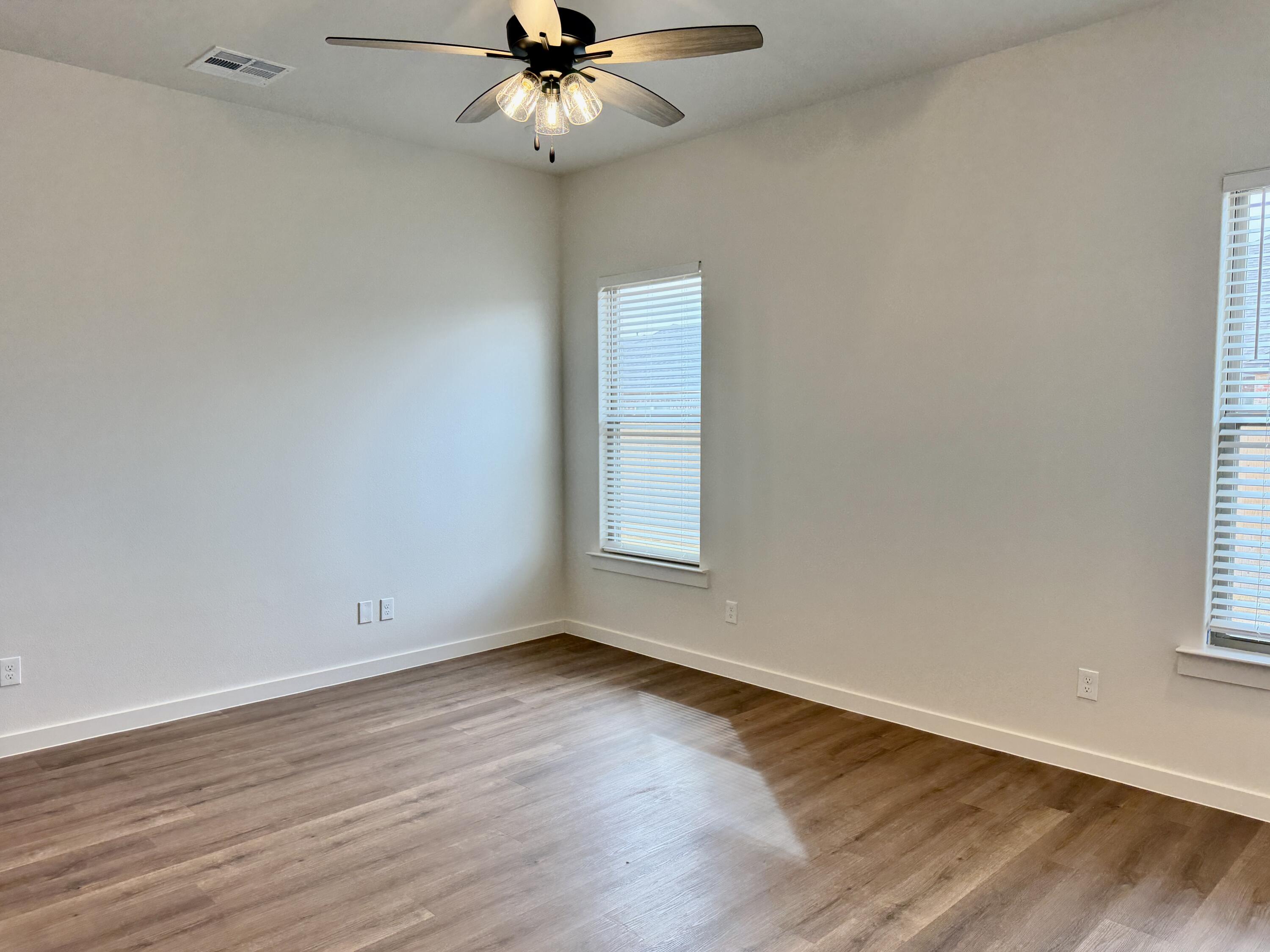 7007 16th Street Lubbock, TX 79416 - Photo 13 of 32 an empty room with wooden floor fan and windows