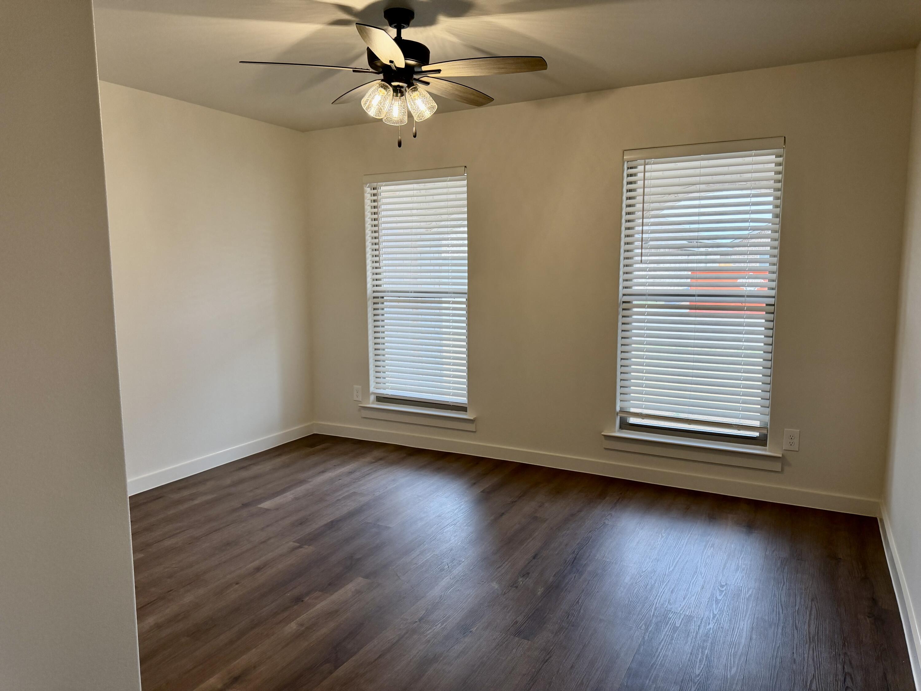 7007 16th Street Lubbock, TX 79416 - Photo 22 of 32 an empty room with wooden floor chandelier fan and windows