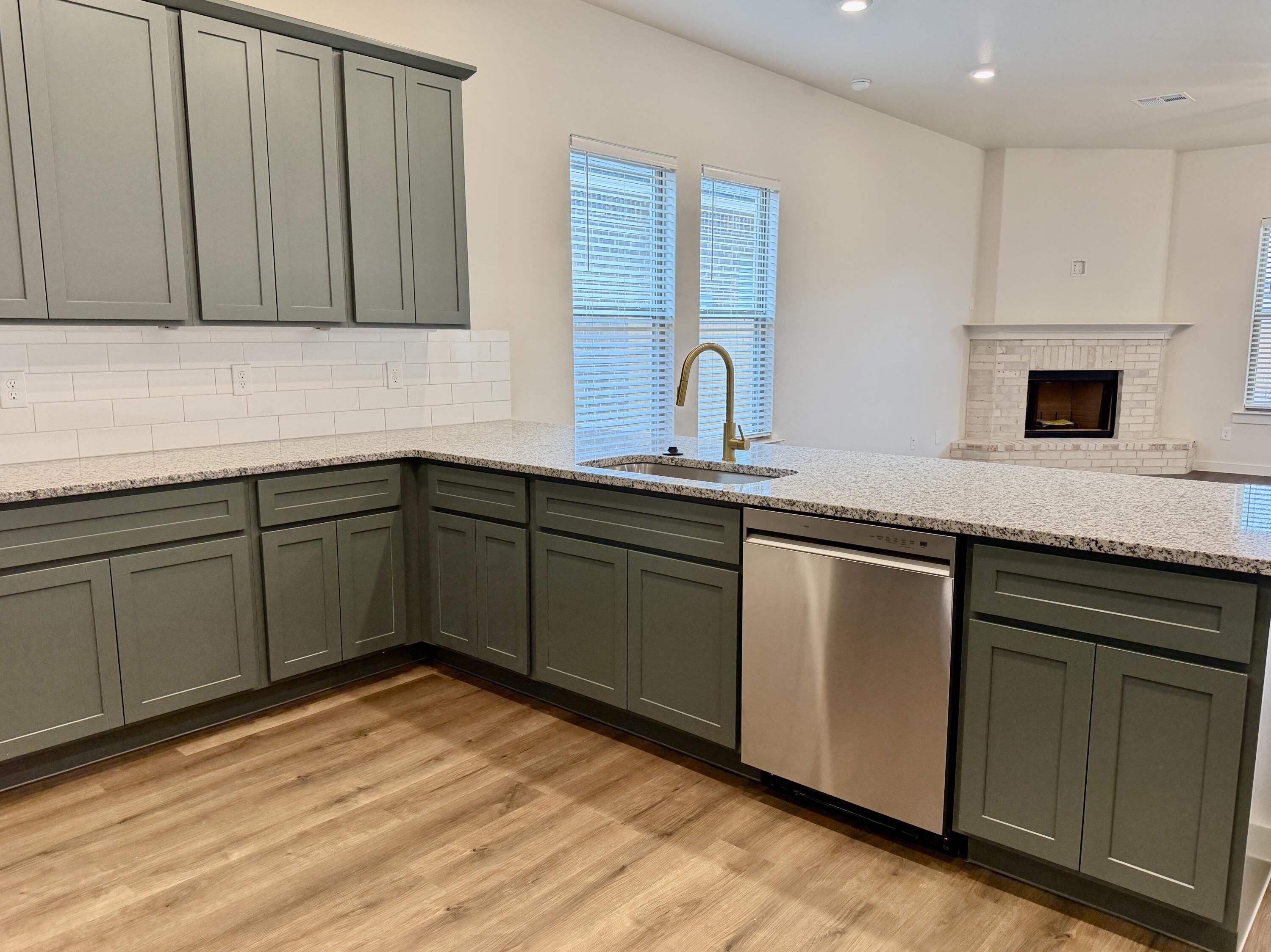 7007 16th Street Lubbock, TX 79416 - Photo 8 of 32 a kitchen with stainless steel appliances granite countertop a sink and cabinets with wooden floor