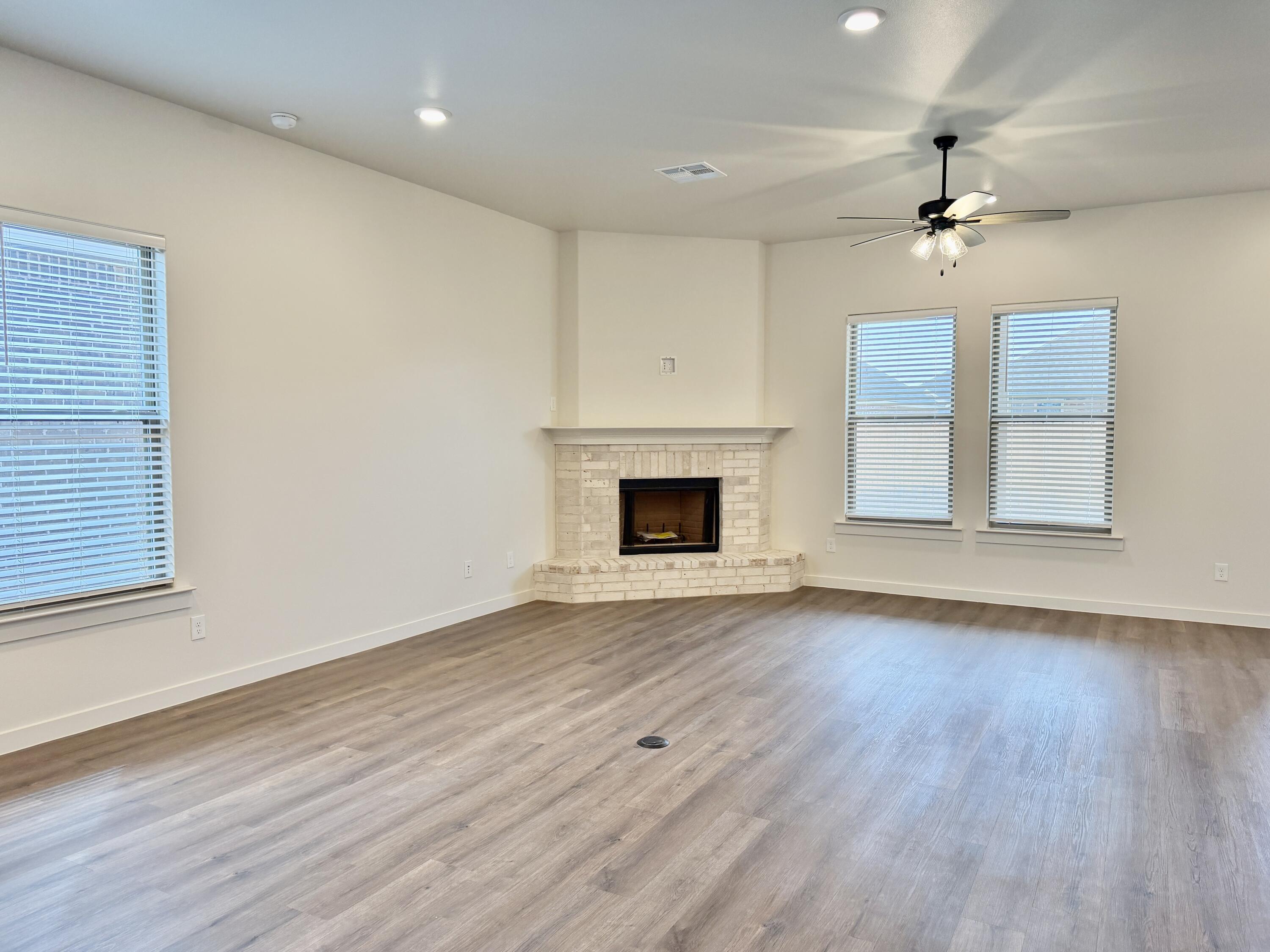 7007 16th Street Lubbock, TX 79416 - Photo 10 of 32 an empty room with wooden floor fireplace and window
