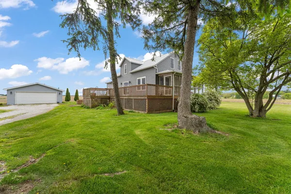 a view of a house with a big yard plants and large trees