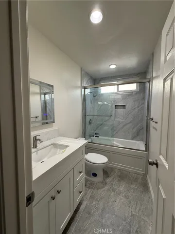 a bathroom with a granite countertop sink toilet and shower