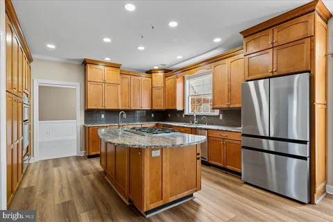 a kitchen with stainless steel appliances granite countertop a refrigerator a stove and a wooden floors