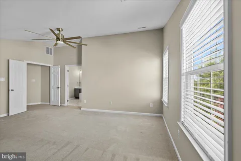 en empty room with windows and ceiling fan