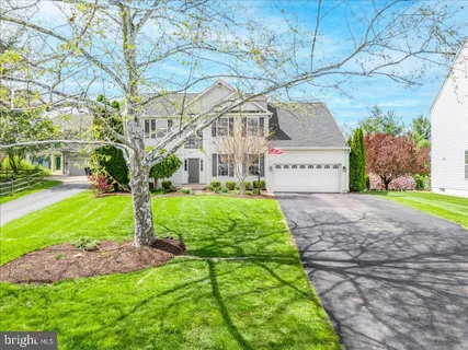 a view of a white house with a big yard plants and large trees