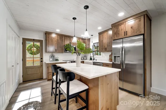 a kitchen with stainless steel appliances granite countertop a sink a stove a refrigerator and island