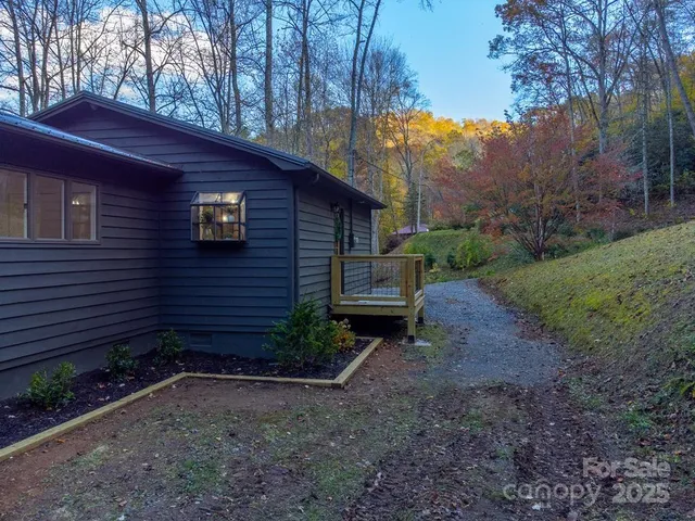 a view of a house that has a small yard and a large tree