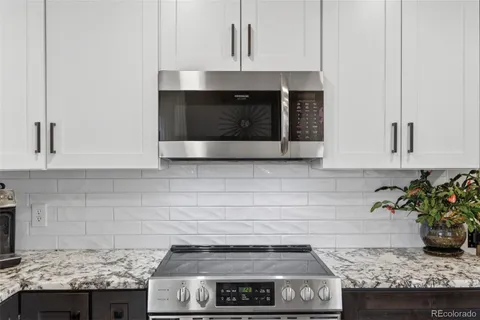 a kitchen with granite countertop a stove and a white cabinets