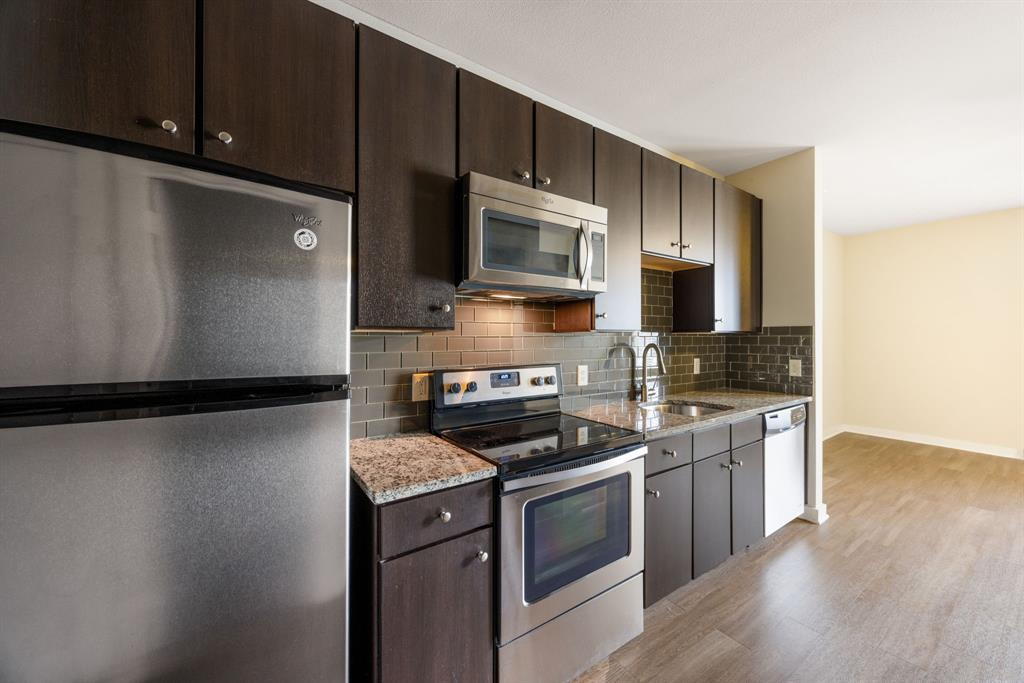 1900 Barton Springs Road, Unit 3013 Austin, TX 78704 - Photo 7 of 27 A well-appointed kitchen features dark cabinetry, granite countertops, and modern stainless steel appliances.