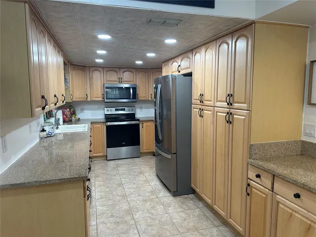 a large kitchen with stainless steel appliances kitchen island granite countertop a refrigerator a stove and a sink