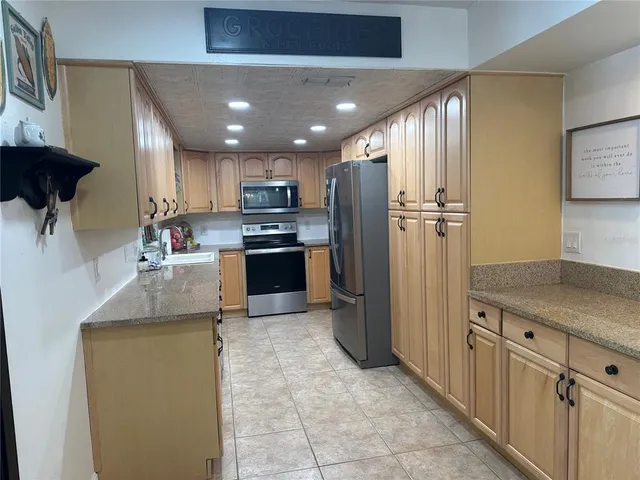a kitchen with kitchen island granite countertop stainless steel appliances a stove refrigerator sink and microwave