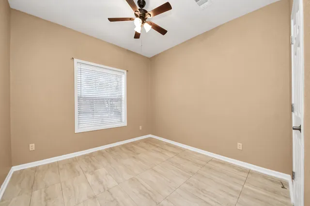 an empty room with a window and a fan