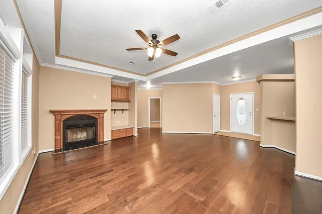 a view of an empty room with wooden floor fireplace and a window