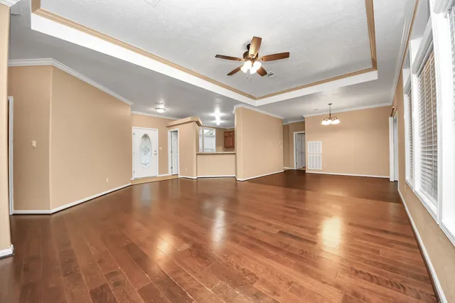 a view of empty room with wooden floor and fan